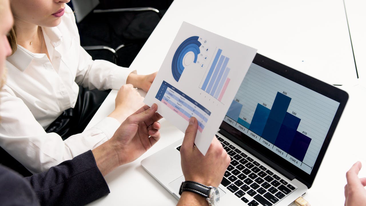 about-us Business professionals discussing data charts and graphs in a modern office setting.